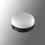 A small, round, dome-shaped electronic device with a white top and black base featuring a yellow button and several ports.
