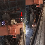 Industrial interior with metal structures, machinery, and rails; a red arrow points to a small white panel on the left, while molten material is visible on the right.