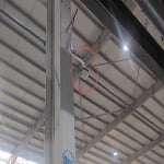 A sn2-uwb-anchor white rectangular device is mounted on a tall metal beam inside an industrial building, with the device circled in red.