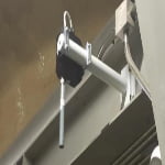 A close-up of an industrial sensor mounted on a metal arm attached to a wall, with wires connected to the device.